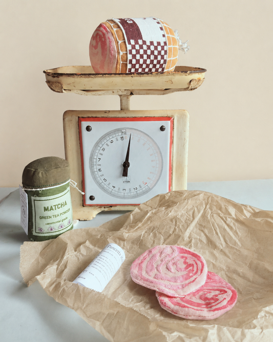 Vintage scale with a Play food fabric rolled pancetta and matcha green tea powder on a light background