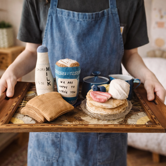 Person holding a tray with play food pancakes, toast, and a bottle of milk.