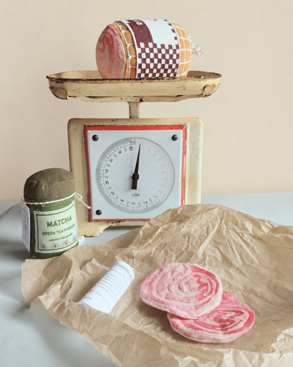 Vintage scale with a Play food  fabric rolled pancetta and matcha green tea powder on a light background