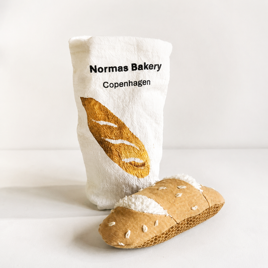 
Handmade fabric baguette with a printed cotton bakery bag on a light studio background.

