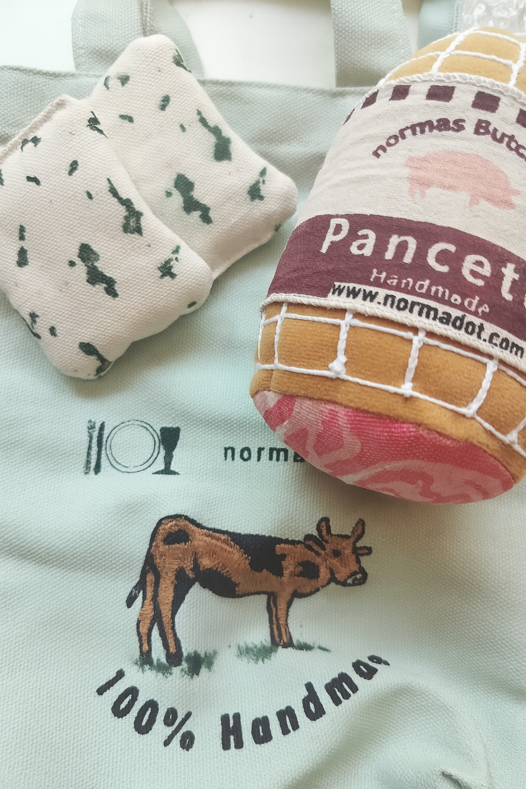 Two fabric products with branding and a cow illustration on a light background