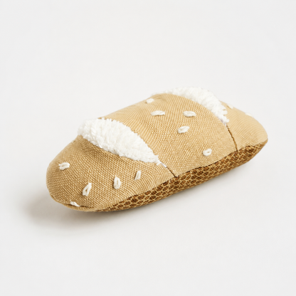 Handmade fabric baguette toy with embroidered seeds and soft white fabric details on a white studio background