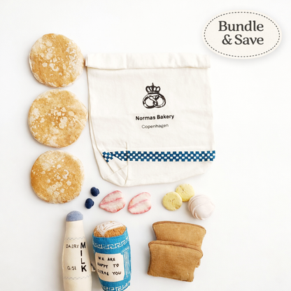 Bakery-themed play food items including bread, cookies, and a milk bottle with a Normas Bakery bag on a white background.