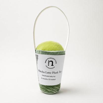 Matcha Latte Plush Toy baby rattle by normadot shown in studio on a light background with white paper packaging handle